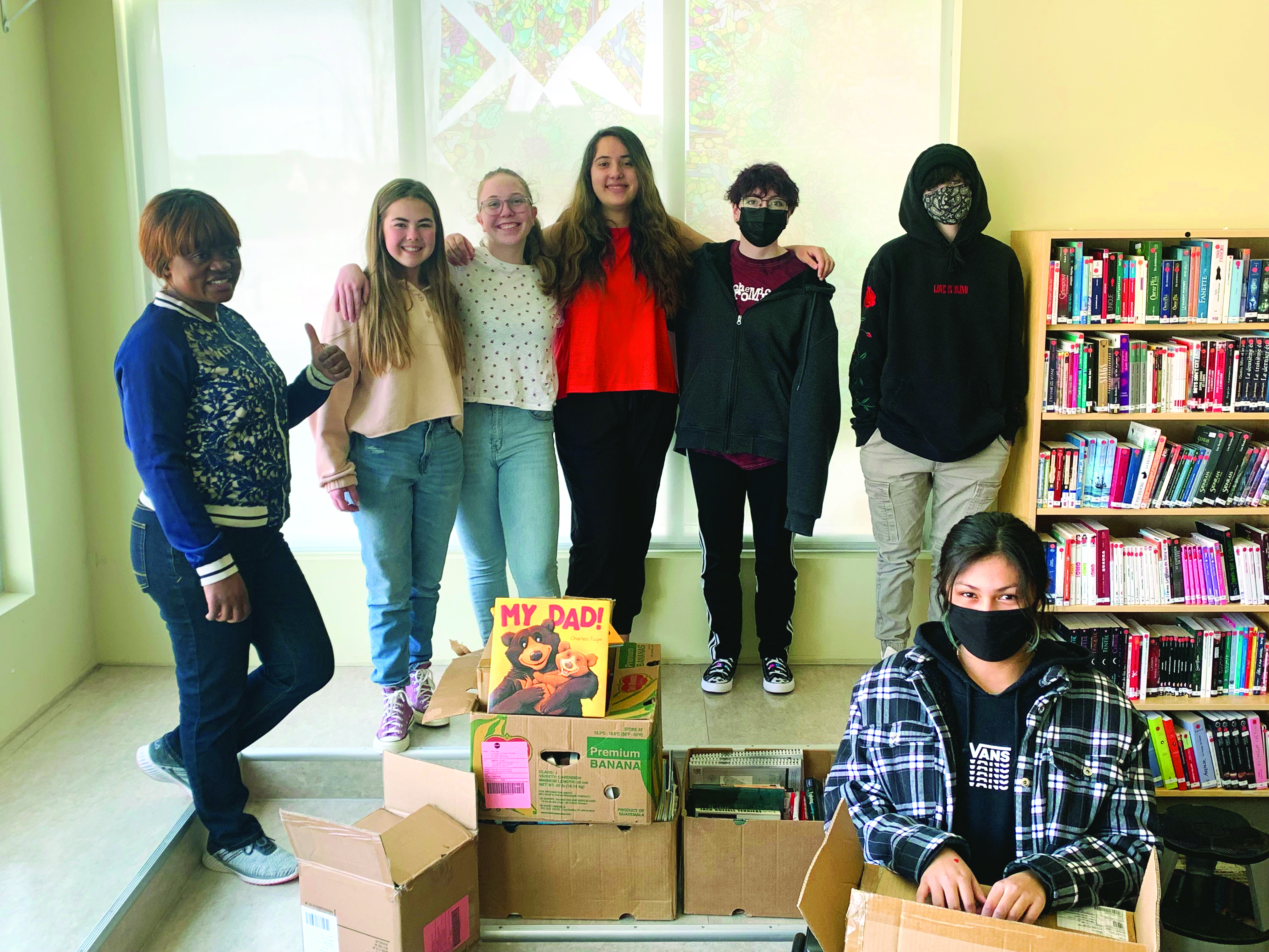 Une partie de la classe de 9e du cours de leadership autour de quelques boîtes de livres qu’ils ont déjà reçus. Crédit : Courtoisie