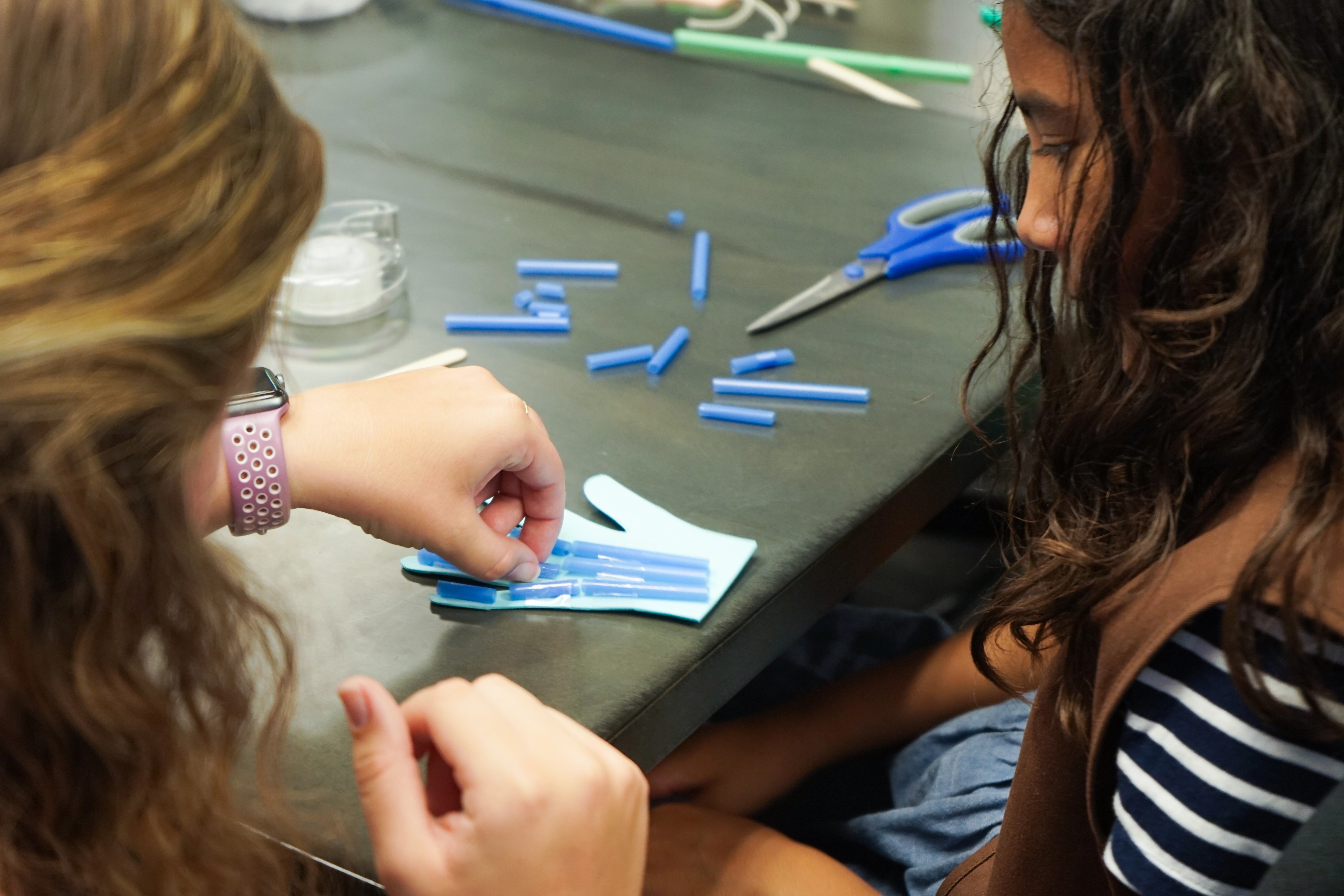 A limbitless intern demonstrating the EMG technology to student visitors