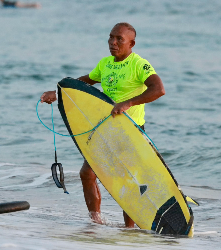 Peselancar memegang papan selancar di pantai pasir putih Bali