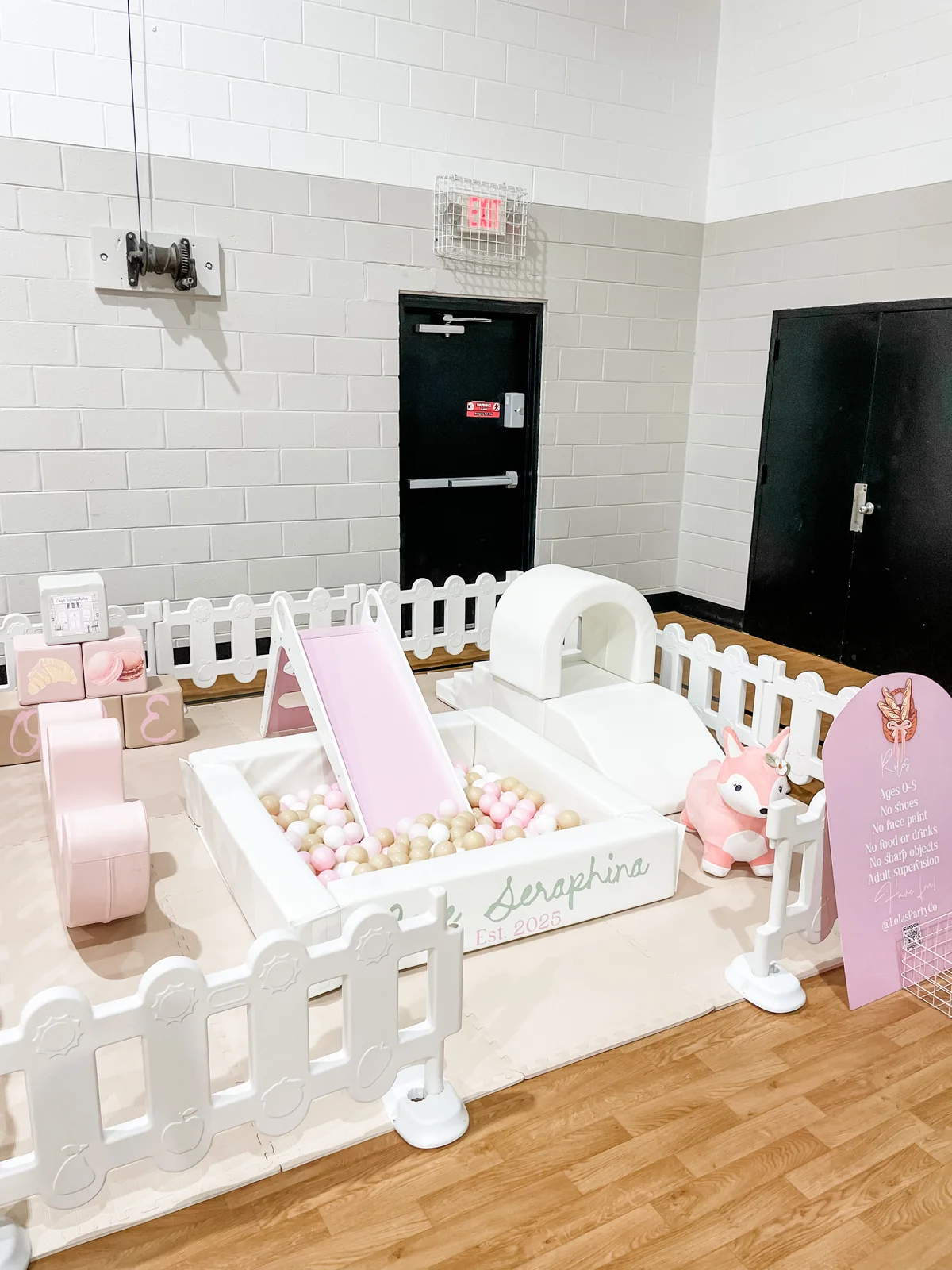 Full indoor soft play setup with pink bounce house, ball pit, and picket fence enclosure