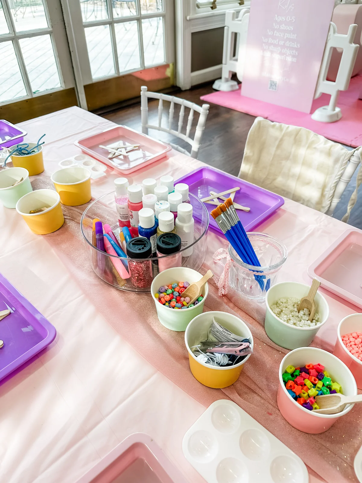 Kids' craft activity table with paints, beads, and supplies for a birthday party