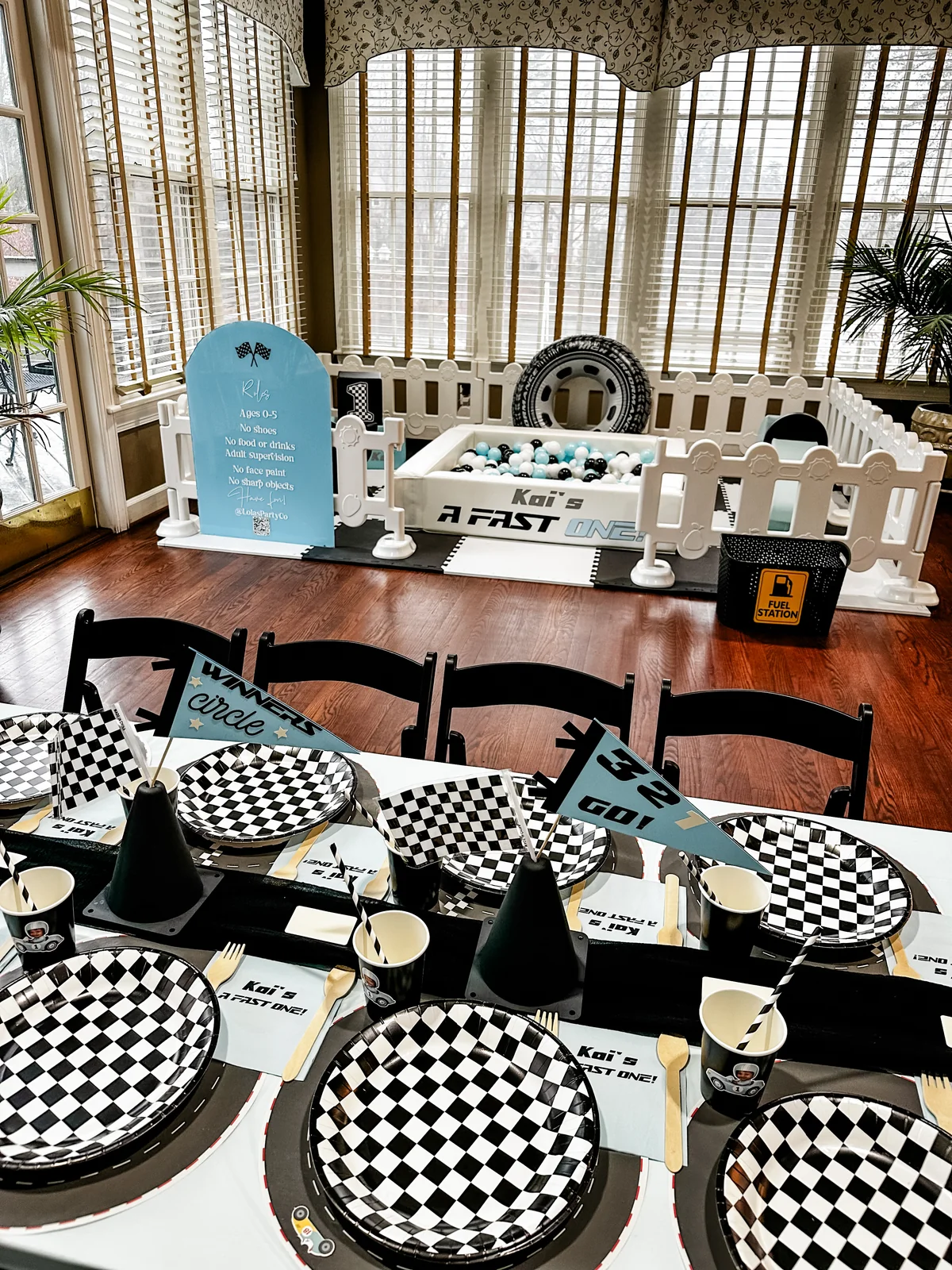 Racing-themed tablescape with checkered plates and party decor alongside soft play setup