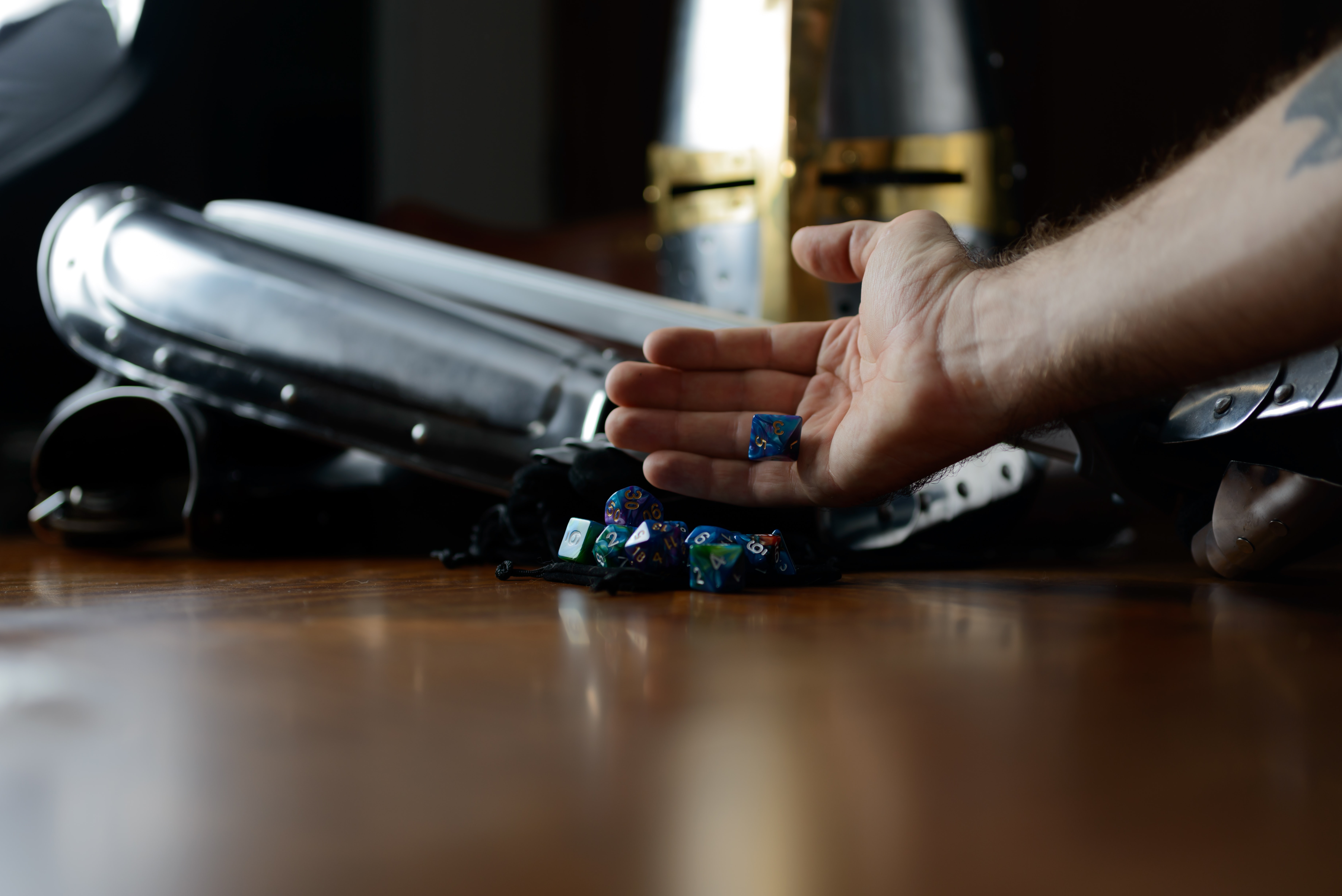 A set of dice being rolled in front of a set of plate mail armor on a table by Carlos Felipe Ramirez Mesa from Unsplash