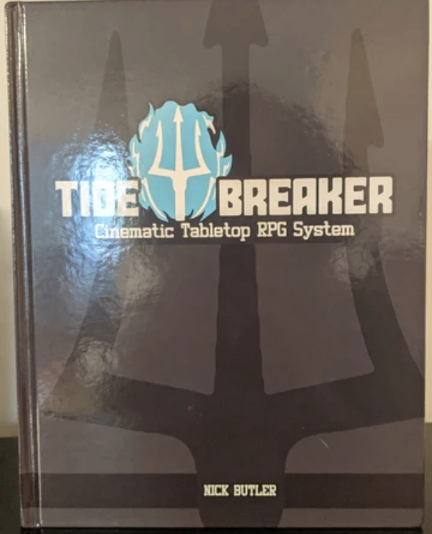 Photo of the hardcover version of the Tide Breaker rulebook. It's mostly grey, with a large black trident as the background, behind the title.