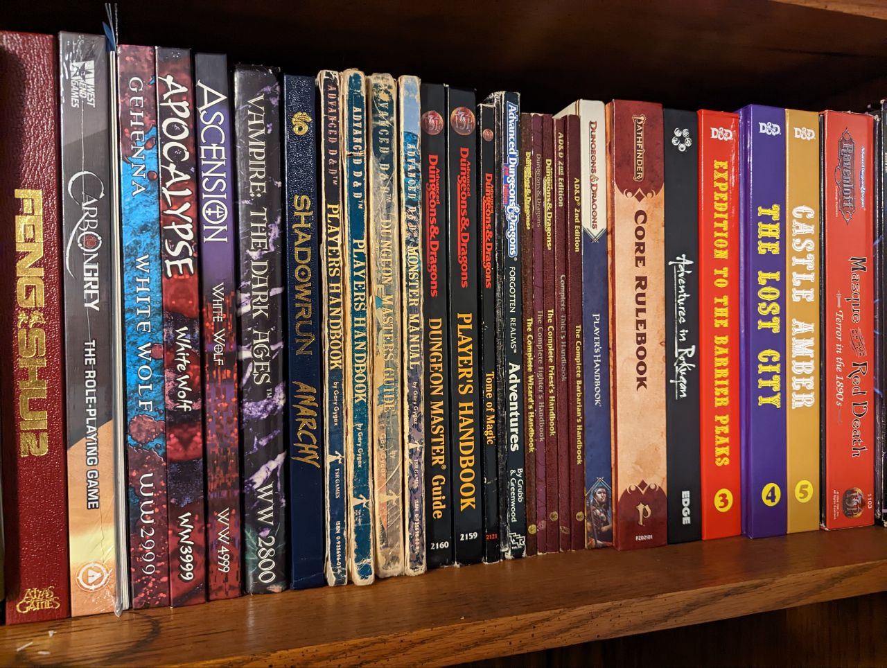 Collection of TTRPG books on a shelf. A mix of games from various generations including D&D, Feng Shui, and Shadowrun