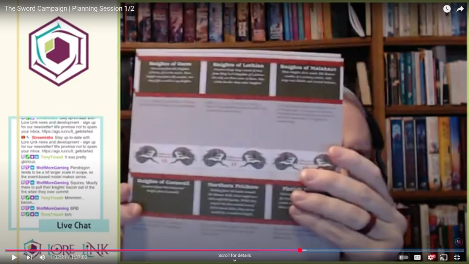 Image of Mike holding part of the Pendragon rules up to the camera. It is slightly blurry, so you can't read anything.