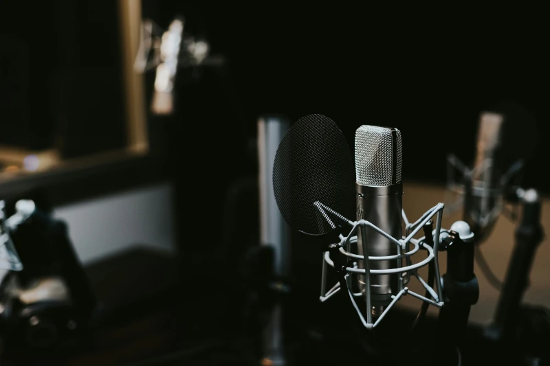 Silver and black condenser microphone shown in a podcast studio.