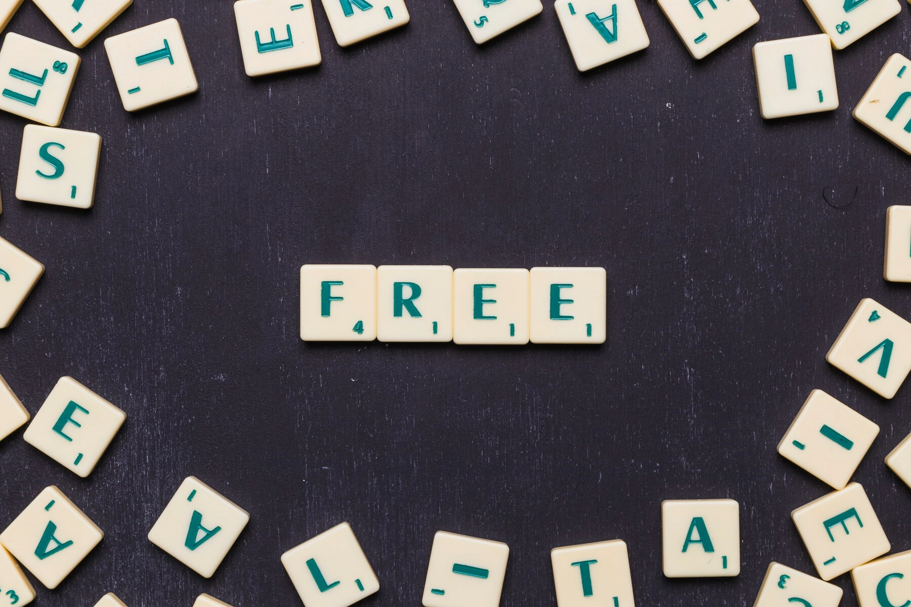 A variety of Scrabble letter tiles, and a group in the middle spell out "free"
