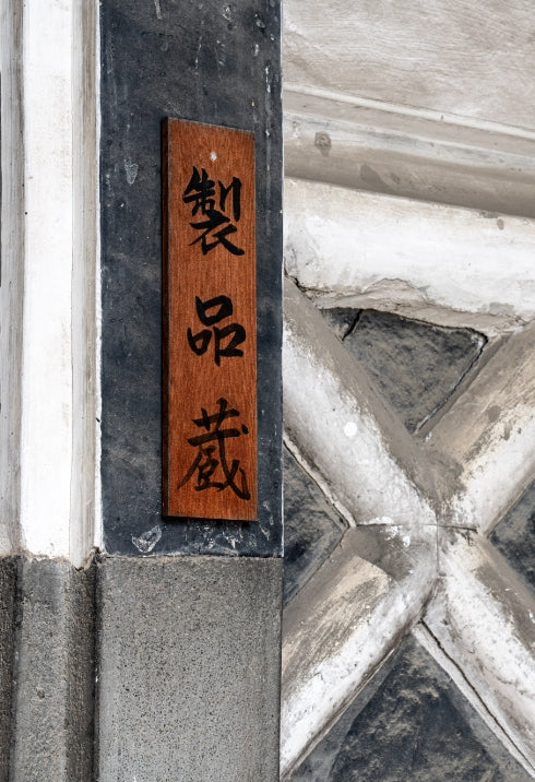 Close-up of a wooden sign reading "Seihinzo" (product storehouse) mounted on the brewery's exterior wall.