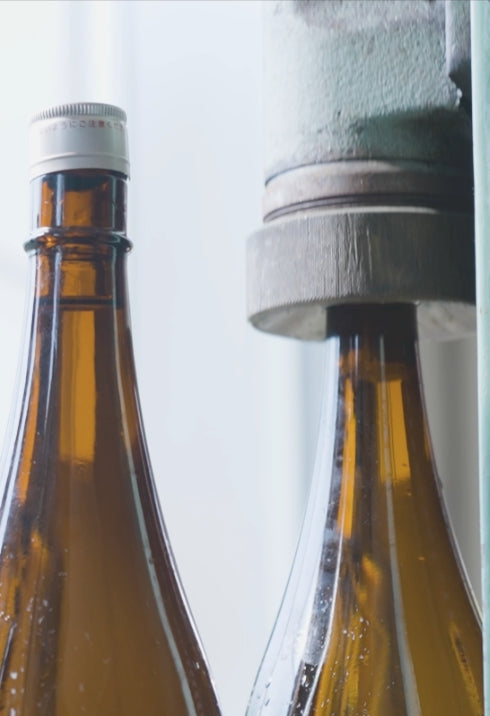 Close-up of bottles being capped during the bottling process.