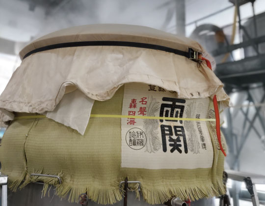 Sake being pressed through a traditional fune press, wrapped in the brewery's fabric.