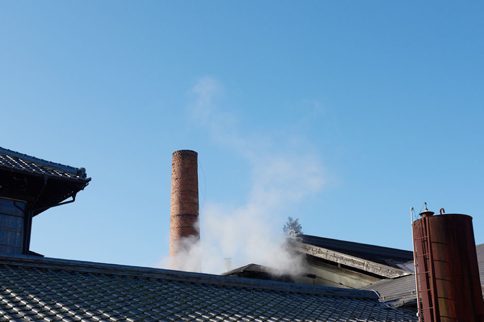 Brick chimney with rising steam above the brewery roof