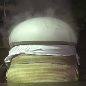 Steamed rice under cloth cover, releasing steam