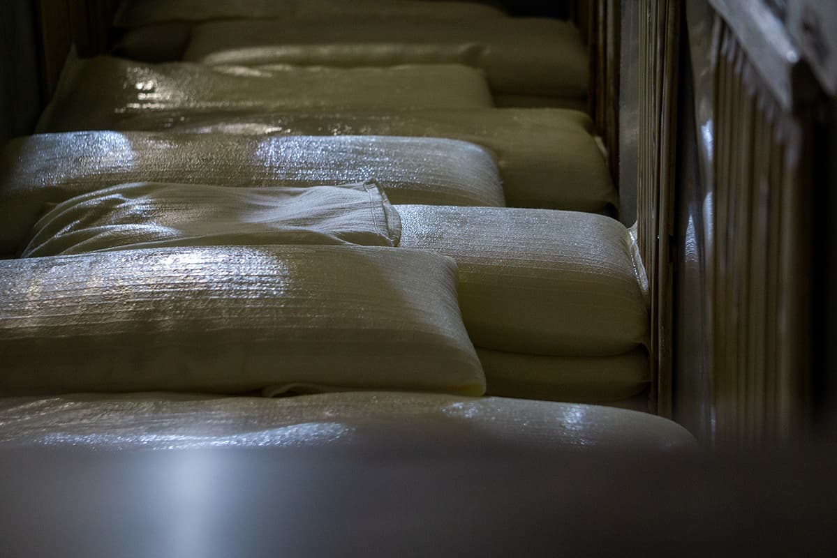 Moromi mash cloth bags loaded into the wooden press trough (fune) before pressing