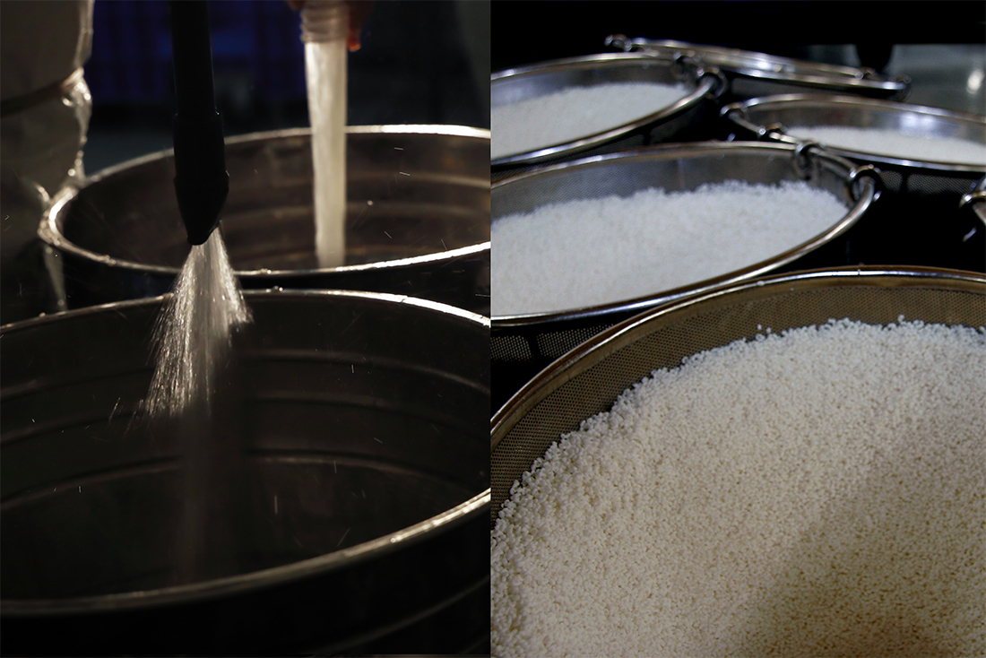 Rice being washed and drained in metal basins during brewing preparation.
