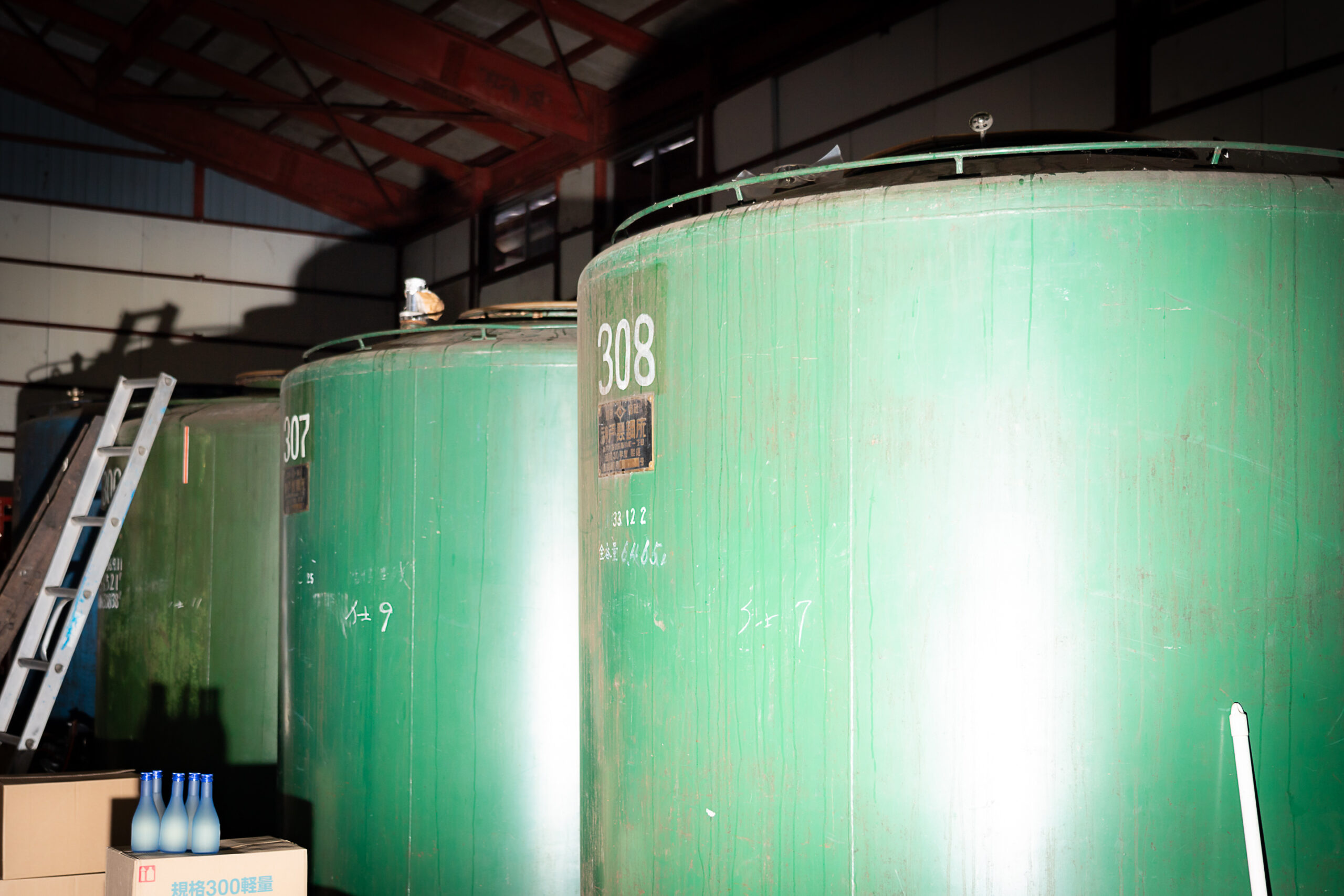 Row of green fermentation tanks inside the brewery