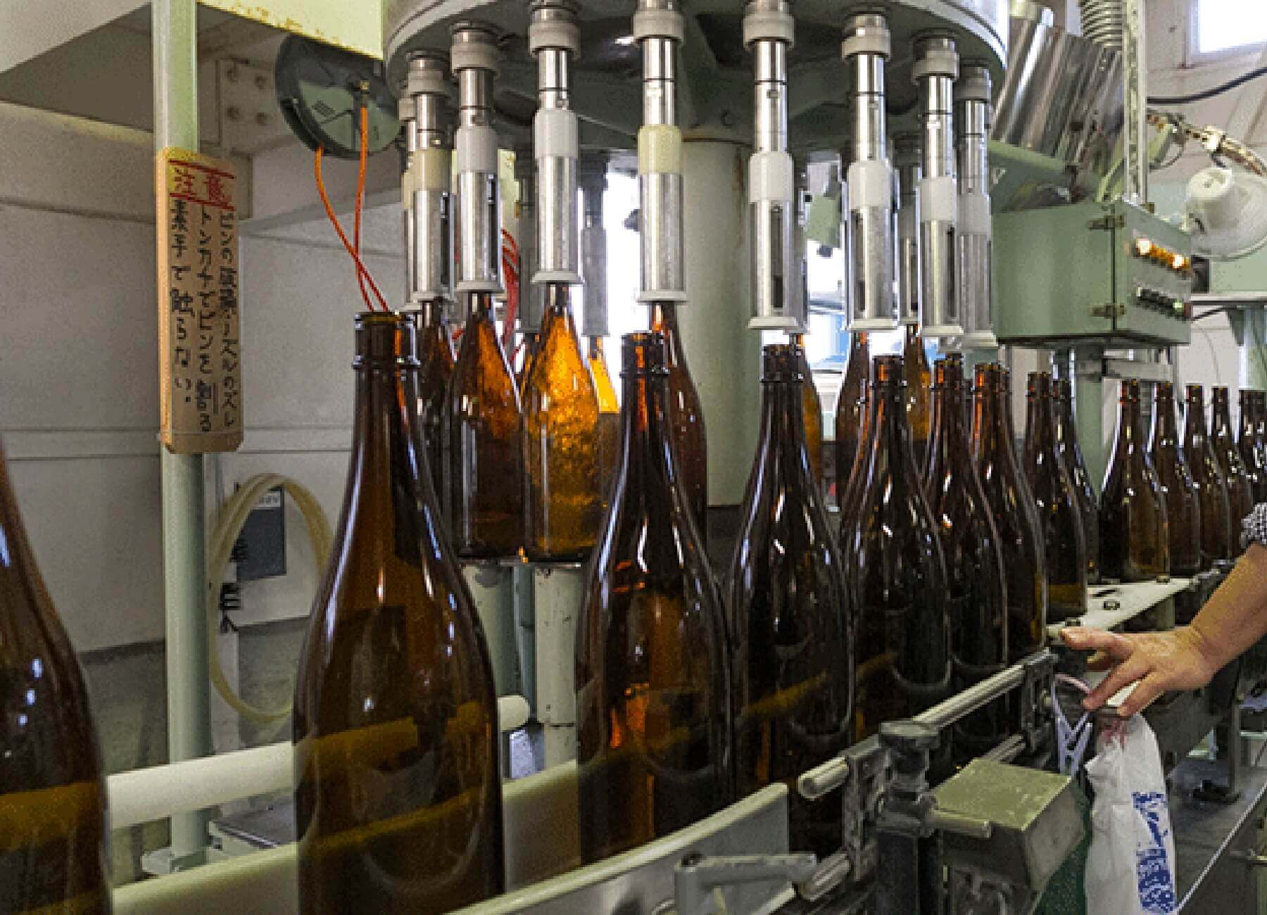 Bottling line filling sake into glass bottles