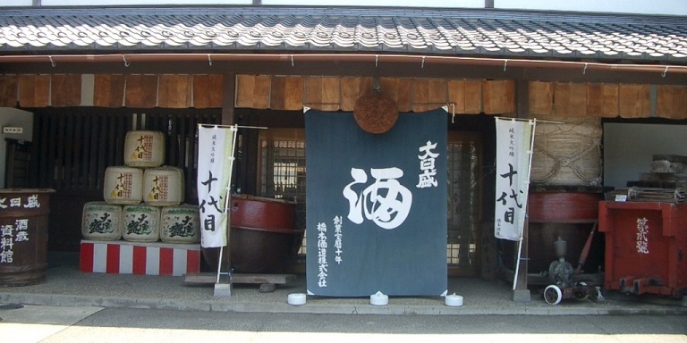 Storefront of the brewery museum with sake barrels and noren curtains