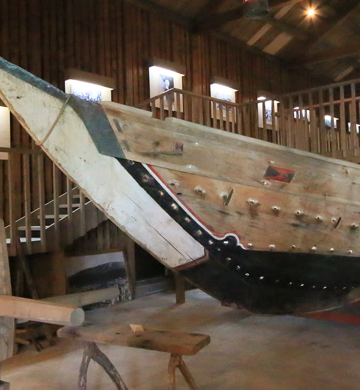 A giant preserved wooden fishing boat on display inside the Senkoku-gura storehouse, telling the story of the herring fishing era.