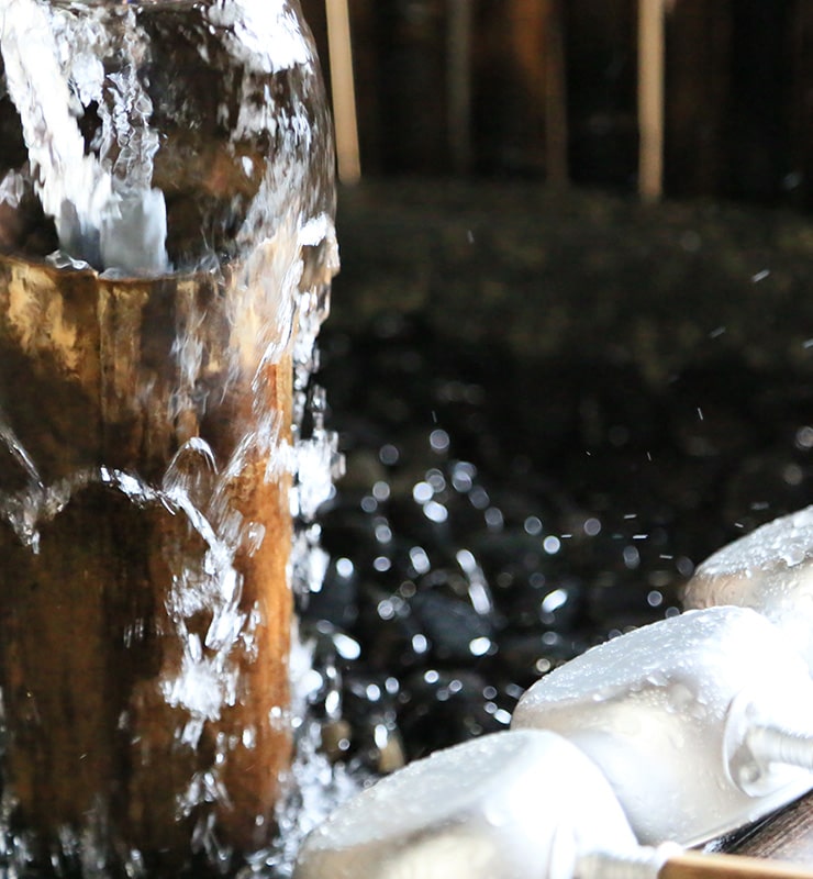 Clear spring water, sourced as snowmelt from the Shokanbetsu mountain range, flowing from a tap inside the brewery.