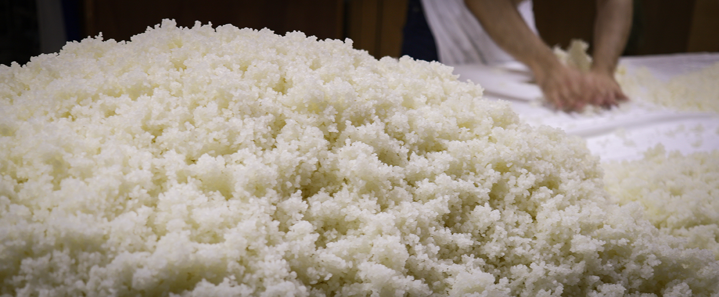 Workers handling freshly steamed rice as it is spread out to cool.