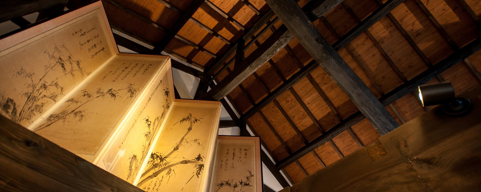 Traditional wooden roof beams and antique painted screens inside the brewery building.