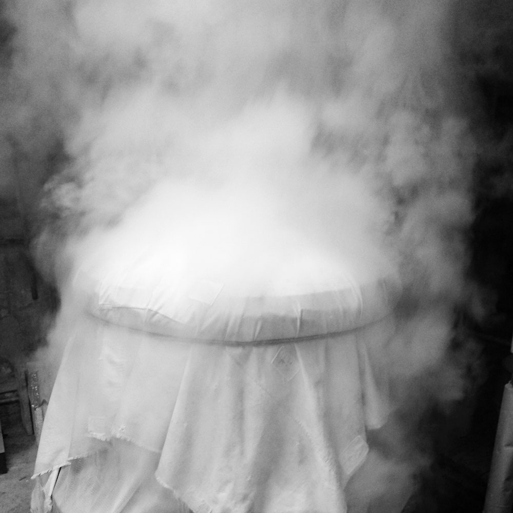 Steam rising from a cloth-covered fermentation vessel, hand-crafted brewing process