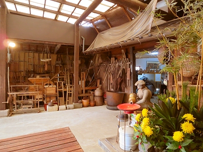 Interior of the brewery museum displaying traditional sake-making tools and old farm equipment