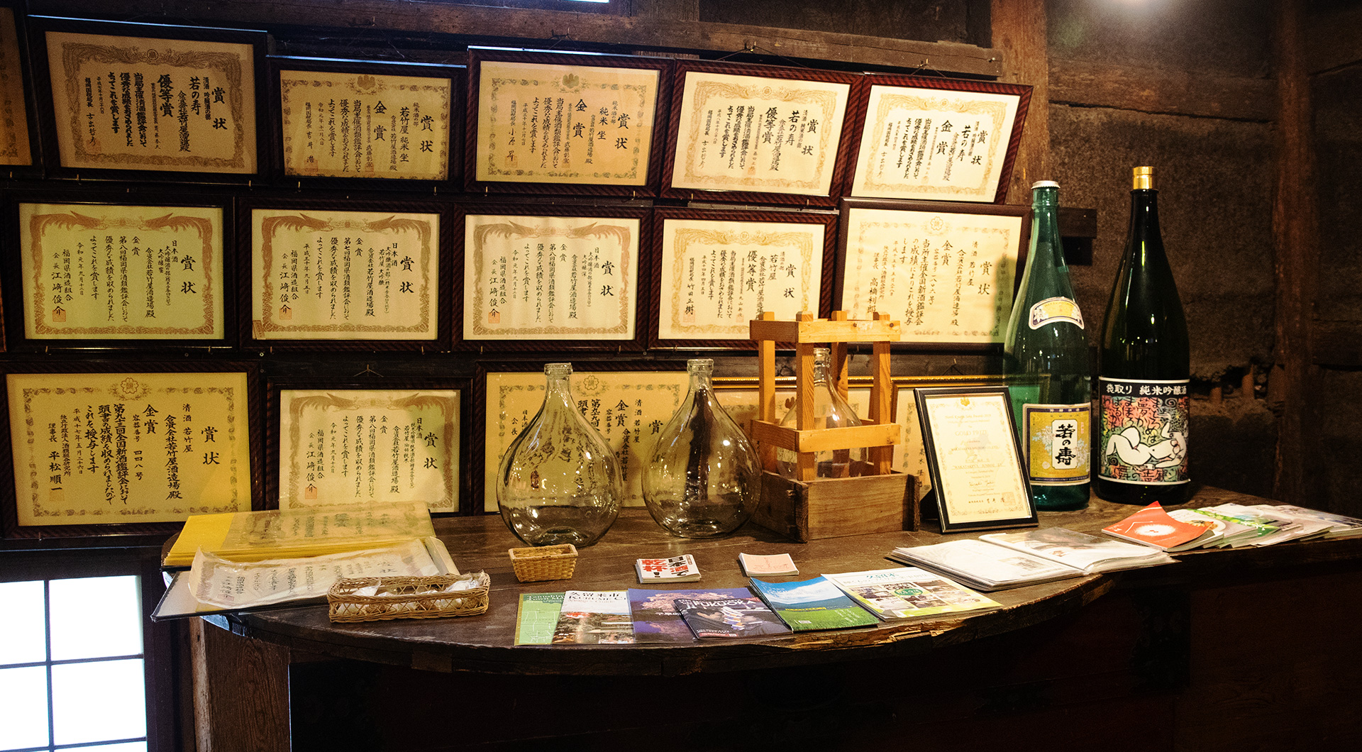 Award certificates and vintage bottles displayed on a counter inside the storehouse.