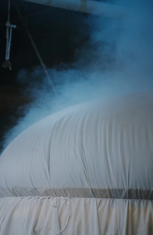Steam rising from a cloth-wrapped moromi (fermenting mash) bag during pressing.