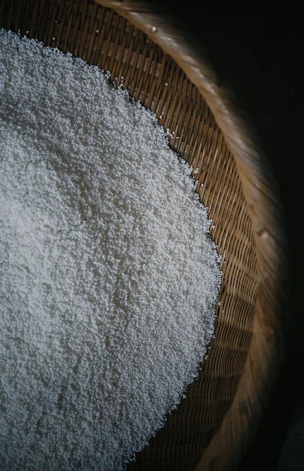Steamed rice spread on a bamboo tray during koji preparation.