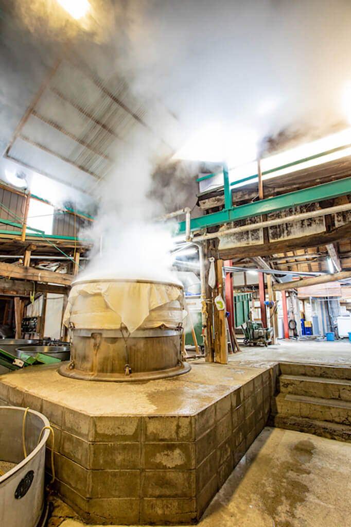 Steam rising from a rice-steaming vat inside the brewery.