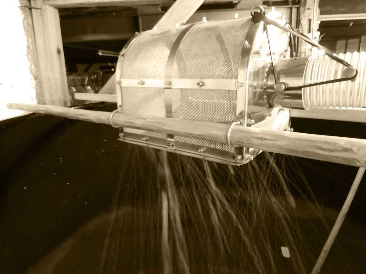 Sake mash being pressed through a filtering drum.