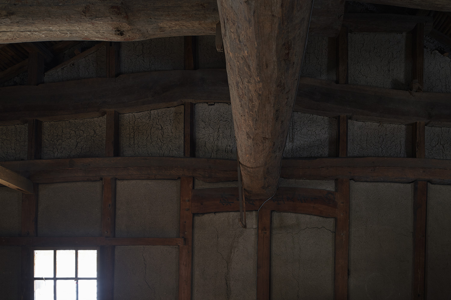 Traditional wooden beams and earthen walls inside the brewery's storage building.