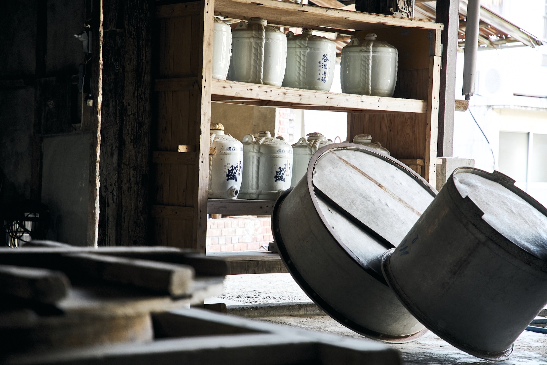 Storage shelves with ceramic sake jars and buckets inside the kura