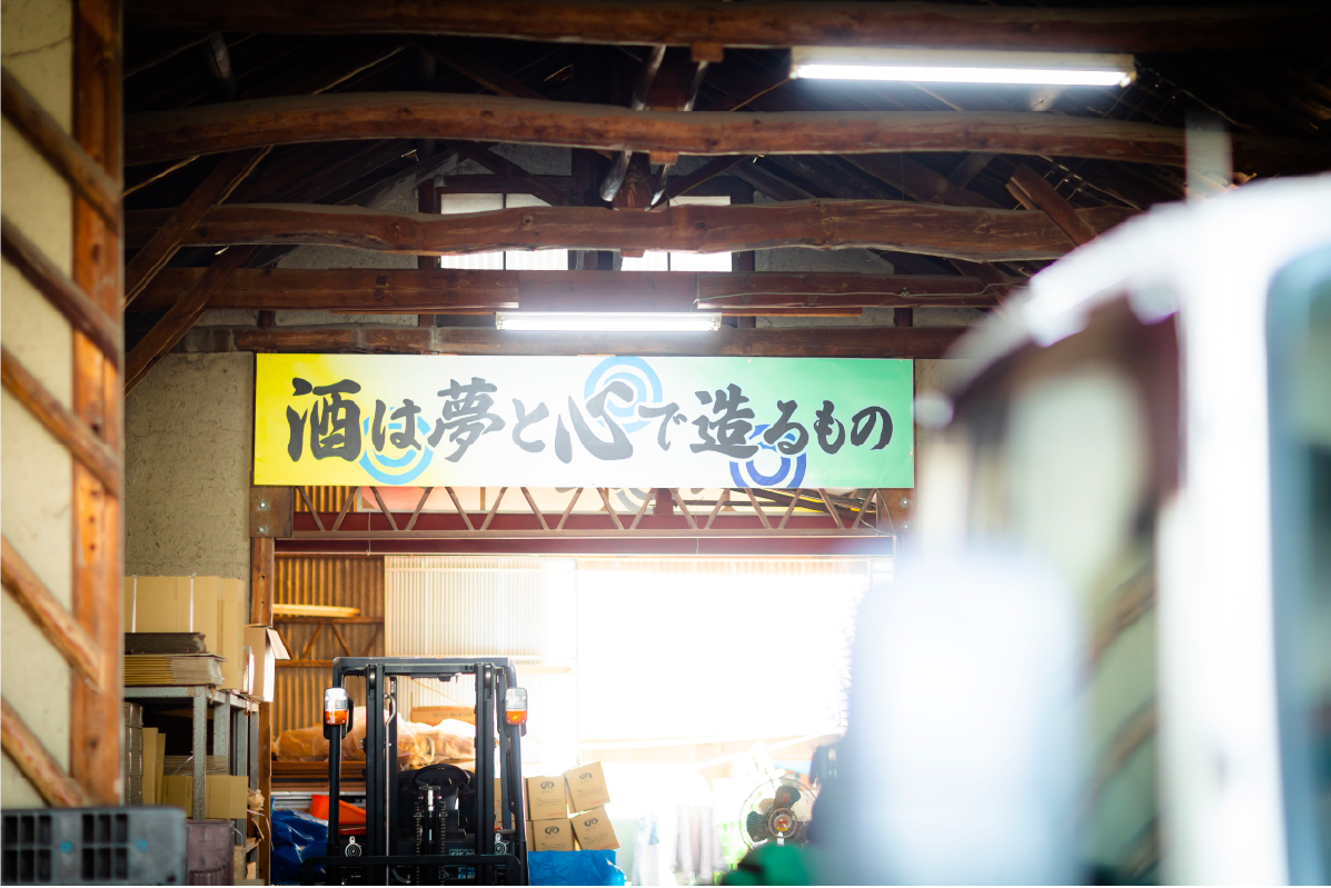 Brewery interior with a banner reading "Sake is made with dreams and heart"