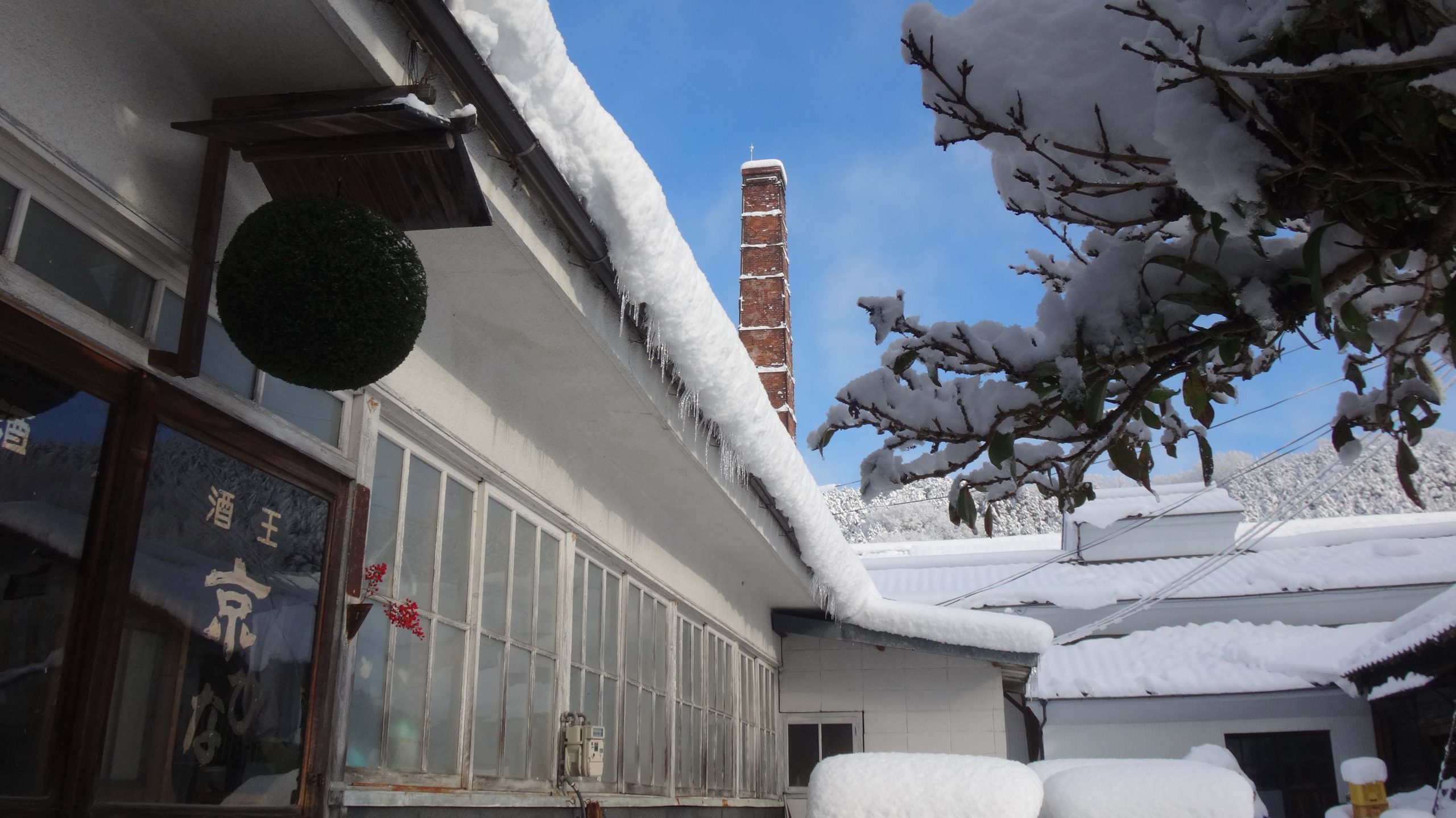 Snow-covered brewery eaves and brick chimney in winter.