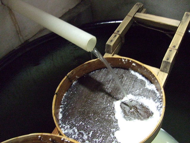 Freshly pressed sake running through a fune press filter into a wooden tub during shibori.