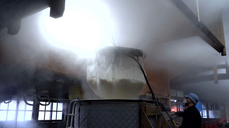 Steam rising during the fukuro-tsuri (bag-hung) moromi pressing process inside the brewery.