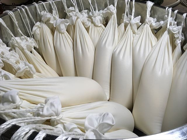 Cloth bags filled with fermenting moromi mash, arranged in a tub before pressing.