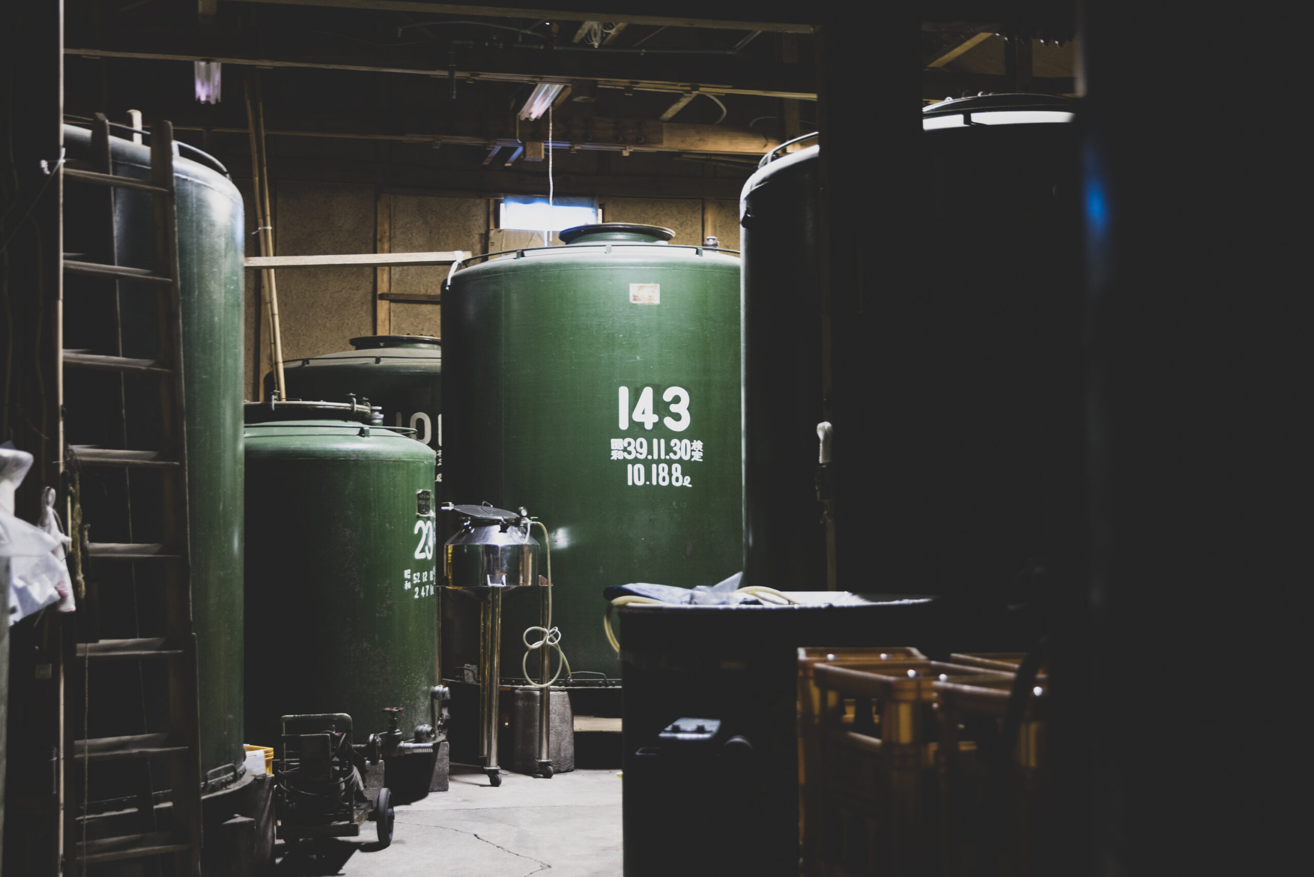 Rows of large green fermentation tanks inside the brewery.