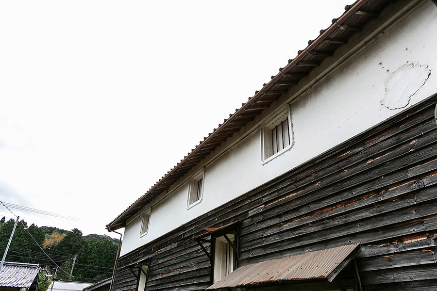 Weathered wooden siding and tiled roof of the storehouse