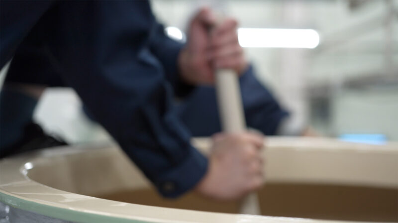 A brewer stirring the mash tank during the shikomi (mashing-in) process.