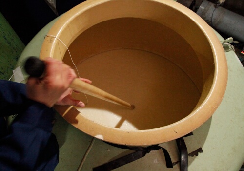 Checking a fermentation tank (moromi) during the brewing process.