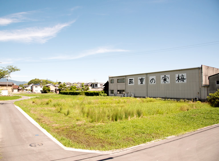 Wide exterior view of the brewery building with the "Mie no Kanbai" name painted on the wall.