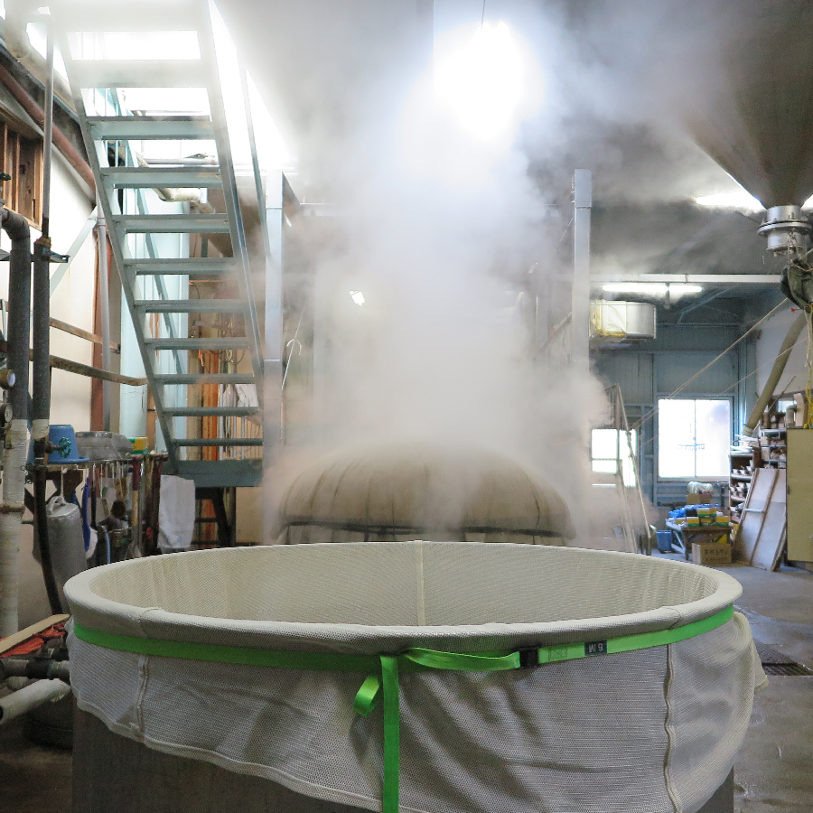 Steam rising from freshly steamed rice during the brewing process.