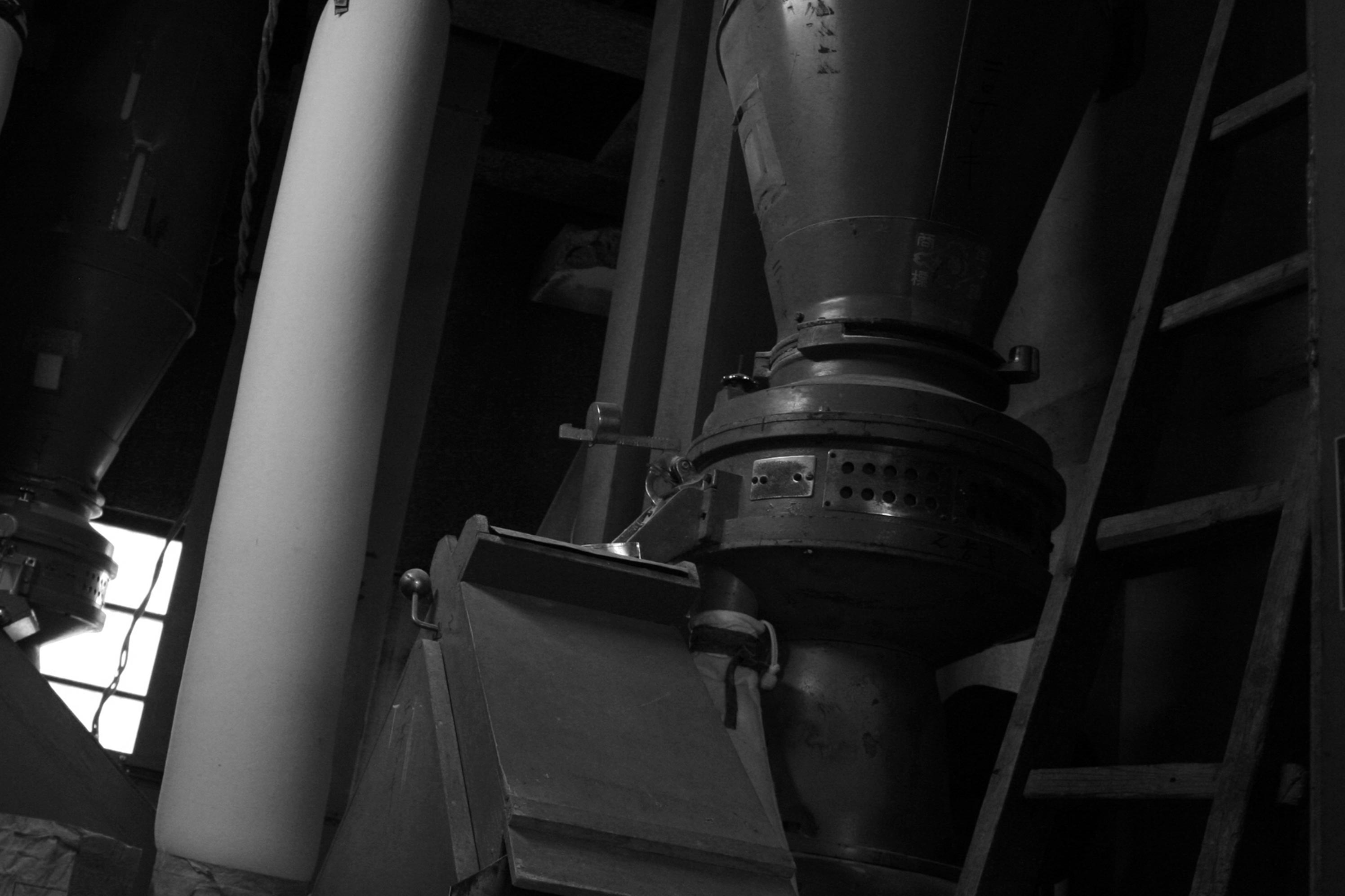 Brewery equipment inside the koji room, seen through the dim interior light.
