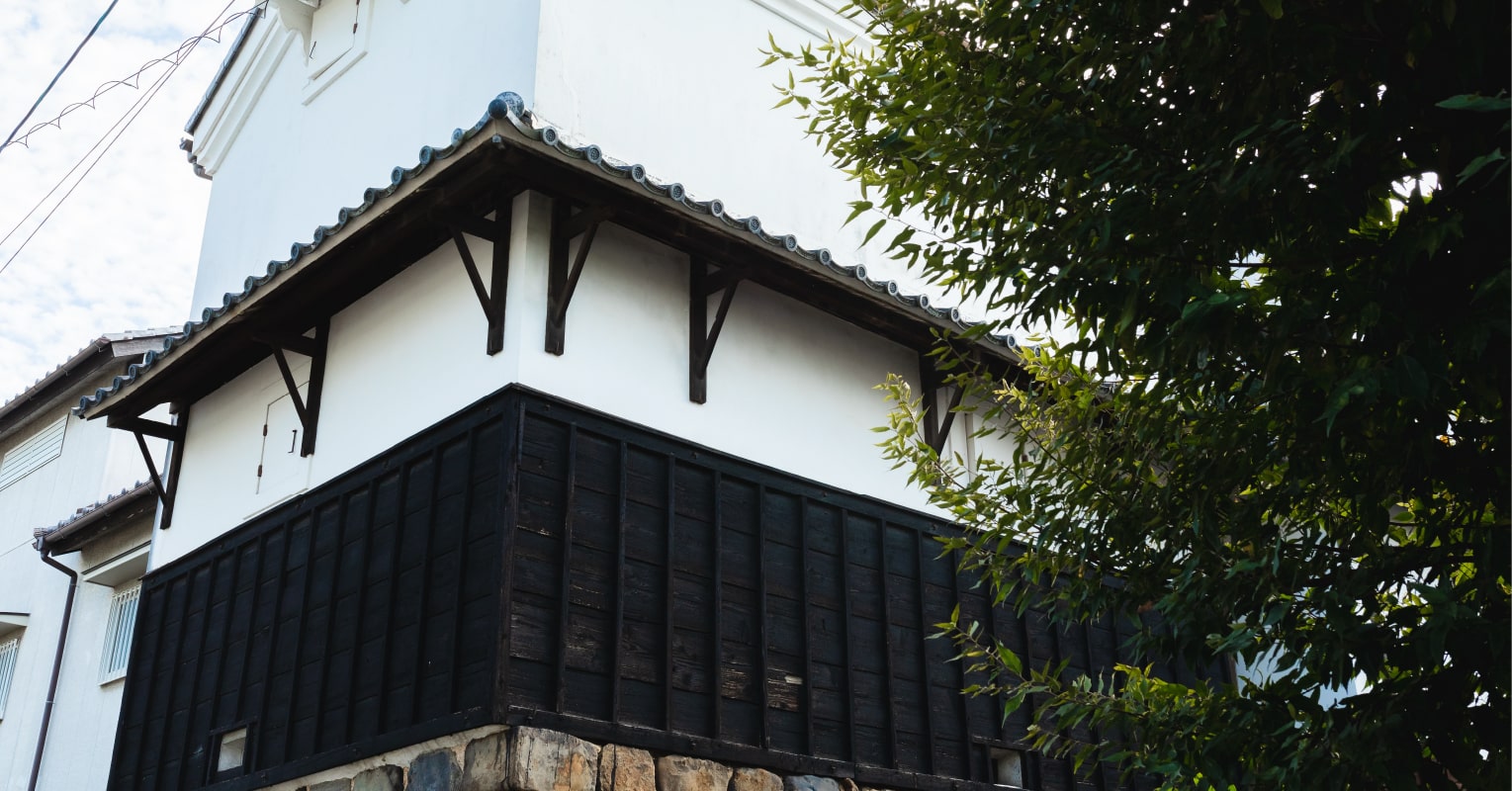 Close-up view of the traditional black-and-white kura storehouse resting on a stone foundation.