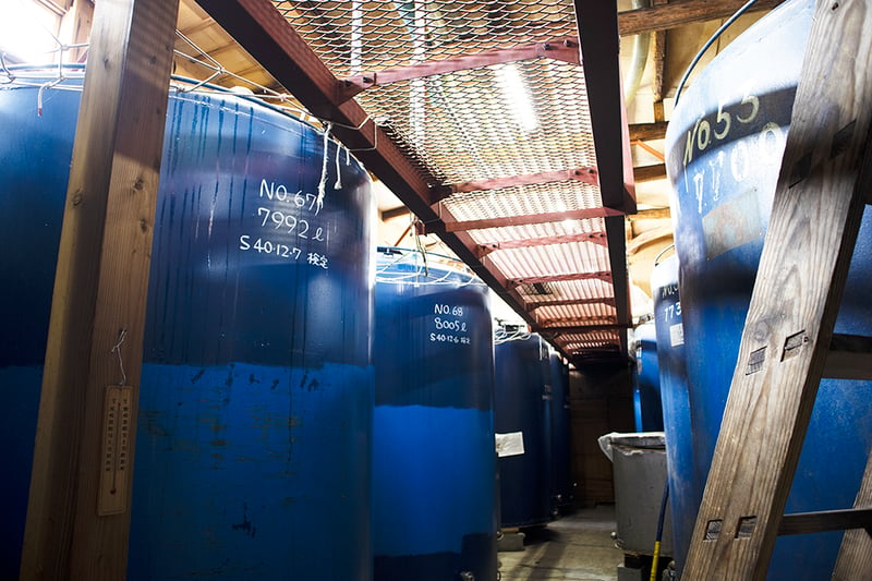 Corridor lined with large blue fermentation tanks inside the brewery