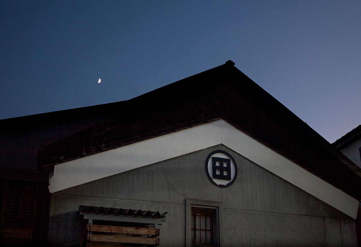 Brewery building gable at dusk with the family crest